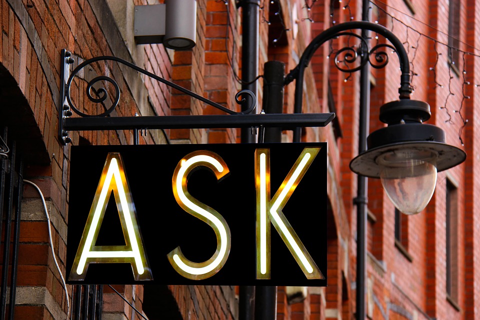 Neon sign displaying the word 'ASK' on a black background.