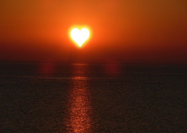 A heart-shaped sun setting over the ocean.